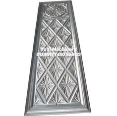 a metal plaque with an ornate design on the front and back side, in silver