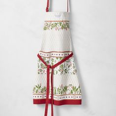 an apron hanging on the wall with a red ribbon around it and a white background