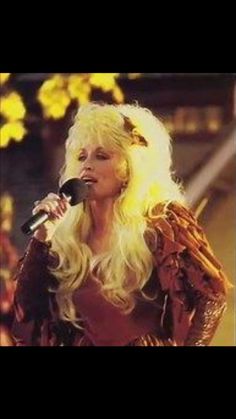 a woman with long blonde hair singing into a microphone