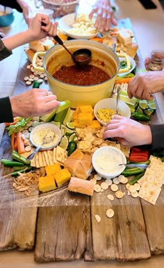 several people are serving themselves food at a long table with plates and bowls on it