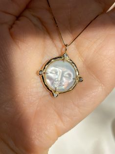 A dreamy 15mm hand-carved Mother of Pearl Moon encircled in gold, set with (4) White Diamonds, set on a solid 14k yellow gold 0.8mm box chain. (Approx. 5.7g.) Inspired in essence by the Impressionist French composer Claude Debussy, Clair de Lune translates to pale blue light or moonlight, and embodies the Divine Feminine energy of the moon, wholly encapsulating the deep sense of serenity found through inner self-awareness, and the strength kept within the gentleness of the heart. Aligns with int Spiritual Yellow Gold Jewelry With Moon Phase, Elegant 14k Gold Sun And Moon Jewelry, Elegant Sun And Moon Design Medallion Jewelry, Yellow Gold Moon Phase Jewelry Round Shape, Spiritual Yellow Gold Moon Phase Jewelry, Handmade Moon-shaped Yellow Gold Jewelry, Luxury Yellow Gold Jewelry With Sun And Moon Design, Spiritual Yellow Gold Jewelry With Sun And Moon Design, Elegant Sun And Moon Medallion Jewelry