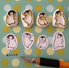 the penguins are drawn on rocks and next to a pair of scissors