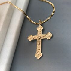 a gold cross necklace is laying on a gray surface