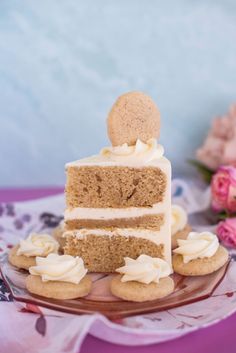 a piece of cake with white frosting and cookies on a plate next to flowers