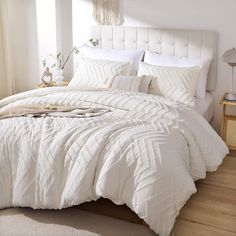 a large white bed sitting in a bedroom next to a window