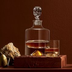 a glass bottle with some liquid in it and two rocks on the table next to it