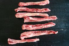 five pieces of raw meat laid out on a black surface