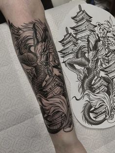 a man's leg with tattoos on it next to a plate that has an image of a dragon