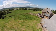 an aerial view of a house in the middle of a green field with people walking around it