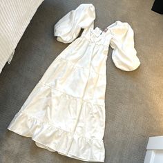 a white dress laying on the floor next to a bed