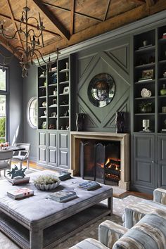 a living room filled with furniture and a fire place under a wooden ceiling mounted book shelf