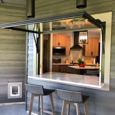 two stools are sitting in front of a kitchen with an open window to the outside