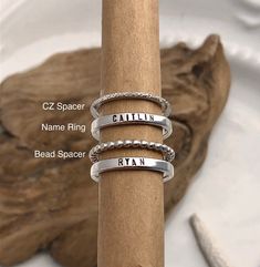 "STERLING SILVER NAME RINGS This listing features beautiful sterling silver rings that are hand stamped with your choice of name or saying as well as spacer ring options. This listing is for ONE ring. The pictures show multiple rings stacked to show the effect of the rings together. Silver rings are solid .925 sterling silver. Rose and yellow gold spacer rings are gold filled. Each name ring measures just over 3mm wide. The sterling silver bead spacer rings measure 2mm wide and the cubic zirconi Posey Ring, Spacer Rings, Rings Stacked, Stackable Name Rings, Rings Hand, Hand Stamped Ring, Multiple Rings, Ring Spacer, Mom Ring