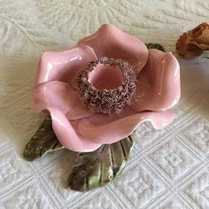 a pink flower sitting on top of a bed next to a vase filled with flowers