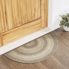 a round rug on the floor in front of a wooden door and potted plant