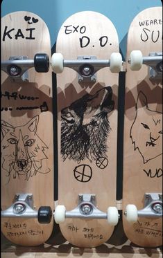 three wooden skateboards with drawings on them