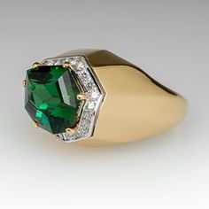 This exquisite cocktail ring is centered with one (1) freeform step cut natural tourmaline set into a six-prong setting and bordered with twenty-two (22), channel set, round brilliant cut diamonds. The ring measures 14.6mm at the top, rises 14.0mm above the finger, tapering to 3.3mm wide and 1.7mm thick at the base of the shank. Signed Schmidt. This ring is currently a size 7. Elegant Emerald-cut Tourmaline Ring, Elegant Emerald Cut Tourmaline Ring, Elegant Tourmaline Diamond Ring With Accent Stones, Elegant Tourmaline Ring With Center Stone, Formal Tourmaline Rings For May Birthstone, Fine Jewelry Tsavorite Diamond Ring For Formal Occasions, Green Diamond Ring With Gemstone Accents For Formal Occasions, Elegant Tsavorite Rings With Polished Finish, Oval Tsavorite Diamond Ring For Formal Occasions