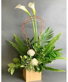 an arrangement of white flowers and greenery in a wooden vase on a gray background