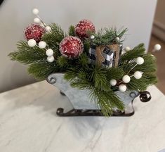 a metal sleigh filled with christmas decorations and pine cones on top of a marble table