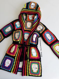 a colorful crocheted jacket is shown on a white surface with a skull in the center