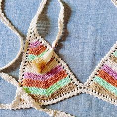 two crocheted purses with tasselled handles on a blue cloth background