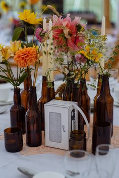 there are many brown bottles with flowers in them on the dining room table set up