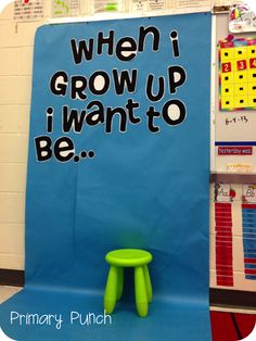 a blue sign with words written on it and a green stool in front of it that says, when i grow up i want to be