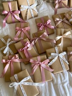 many wrapped presents on a bed with pink ribbons and bows are laid out in the shape of crosses