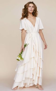 a woman in a long white dress holding a bouquet