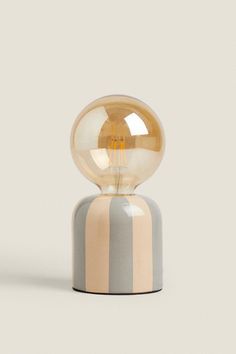 a light bulb sitting on top of a striped tablecloth covered base with a gold sphere