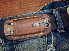 a leather belt with a metal buckle on it and some jeans in the back pocket