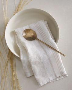 a white plate topped with a spoon next to a napkin on top of a table