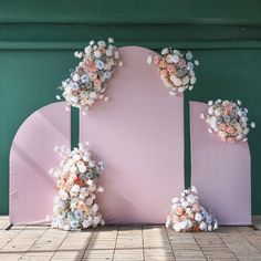 flowers are placed on the back of a pink backdrop for an outdoor wedding ceremony in front of a green wall