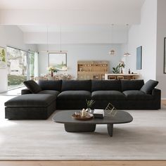 a living room with a large black couch and coffee table in the middle of it