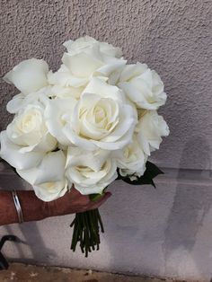 a person holding a bouquet of white roses