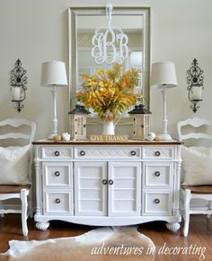 a white dresser with flowers on top and a mirror above it that says give thanks