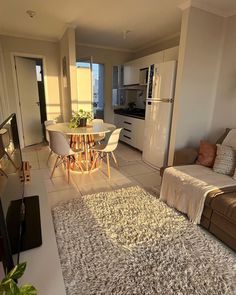 a living room filled with furniture and a dining table next to a refrigerator freezer