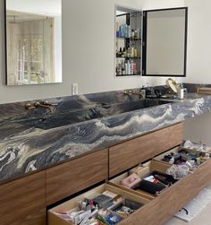 a bathroom vanity with two sinks and drawers underneath the mirror, in front of a large mirror