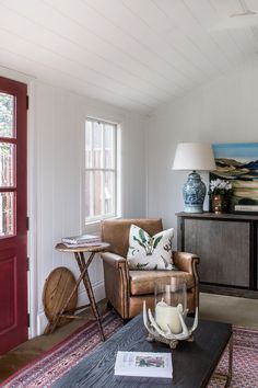 a living room filled with furniture and a painting on the wall next to a coffee table