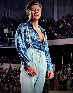 a man in blue pants standing on top of a stage with an audience behind him