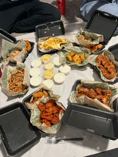 a table topped with lots of trays filled with food