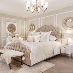 a large white bed sitting in a bedroom next to two nightstands and a chandelier