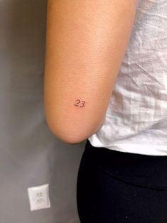 a woman with a small tattoo on her left arm and the number 25 behind her back