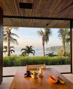 a wooden table with fruit on it in front of an ocean view