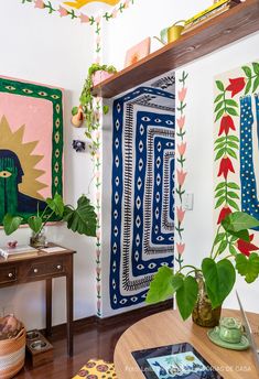 a living room filled with furniture and paintings on the wall behind a wooden coffee table