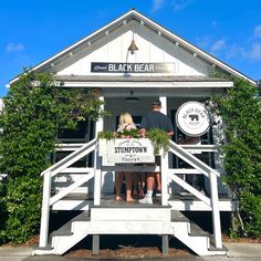 two people standing on the porch of a white building with a sign that says black bear