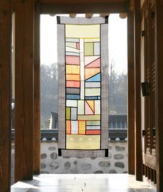 a stained glass window hanging on the side of a building with stone walls and pillars