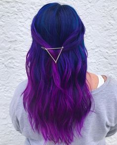 a woman with purple and blue hair wearing a triangle shaped clip in her hair, back view