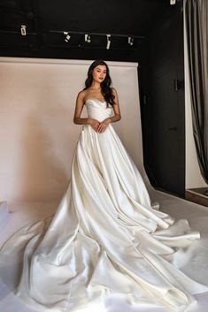 a woman in a white wedding dress posing for a photo with her hands on her hips