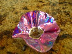 a shiny pink flower sitting on top of a marble countertop next to a sink